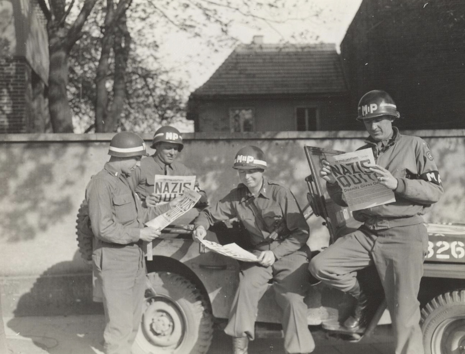 Four MPs take a break along a German road to read in the "Stars and Stripes" newspaper about the German surrender 